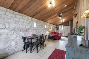 Ein rustikaler Essbereich mit Steinwand, Holzbalkendecke und einem Esstisch mit Stühlen.