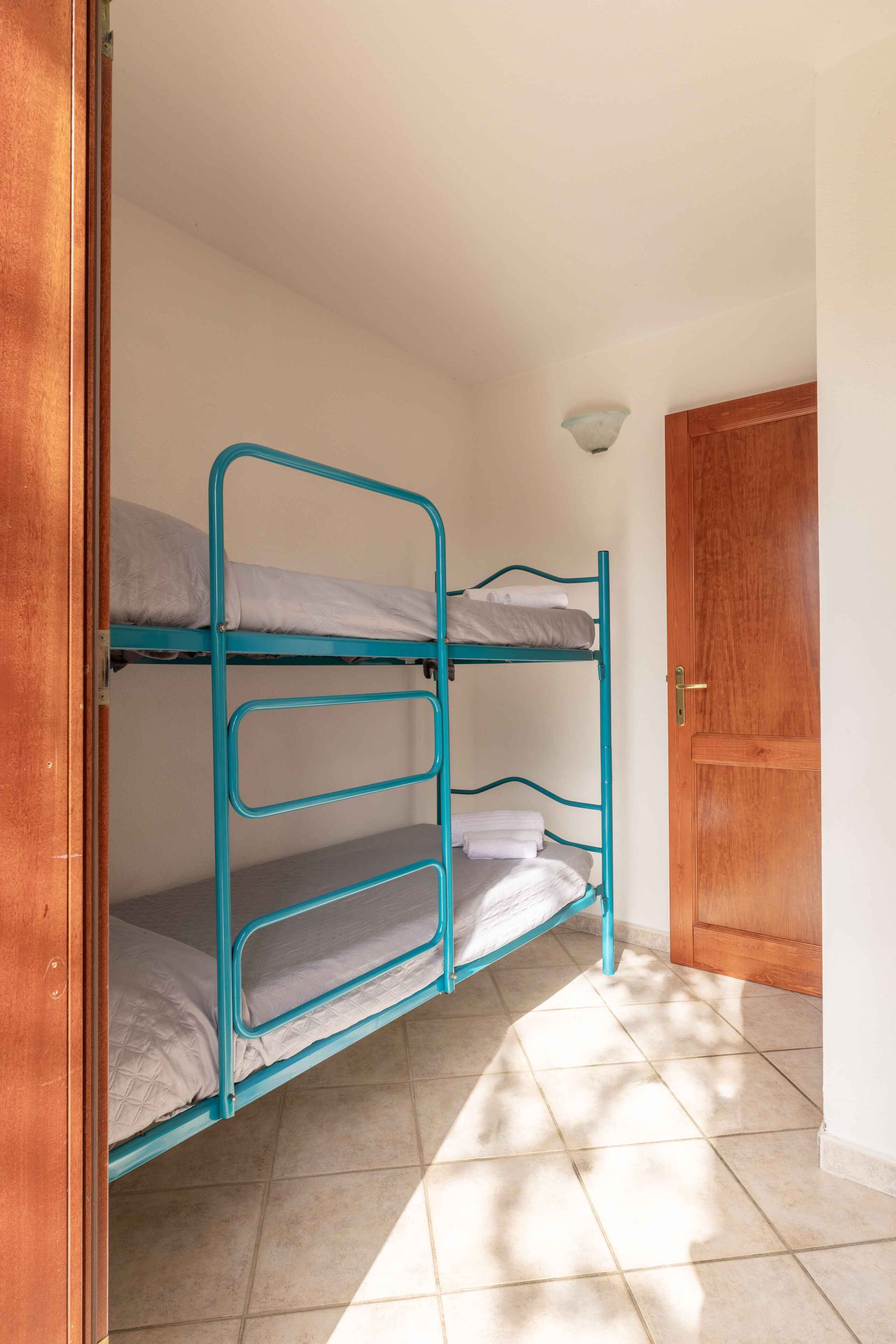 A bunk bed with a wooden door and a light fixture in the corner.