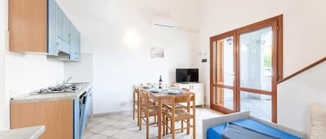 A compact kitchen with a dining area, a small seating area by a window, and a TV.