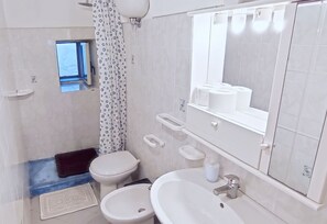 A modern bathroom with a toilet, bidet, sink, and a window. - Simple Cozy family apartment in villa with pool (Pantelleria)