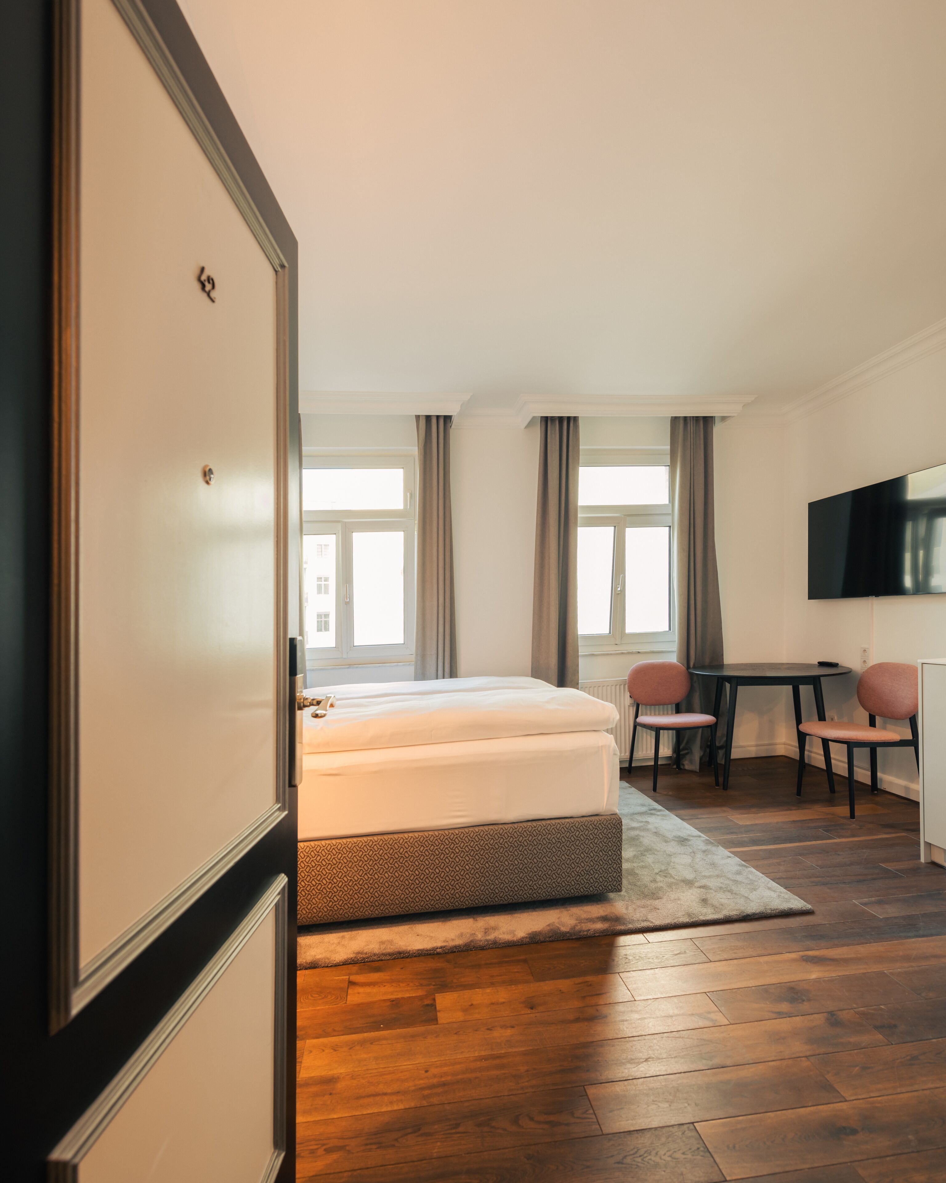 Une chambre d’hôtel avec un lit, un bureau, une chaise, une télévision et une fenêtre.
