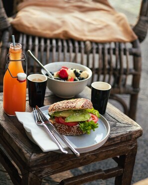 A meal with a sandwich, salad, and drinks on a wooden table with a chair in the background. - Bob W Berlin Mitte (Berlin)