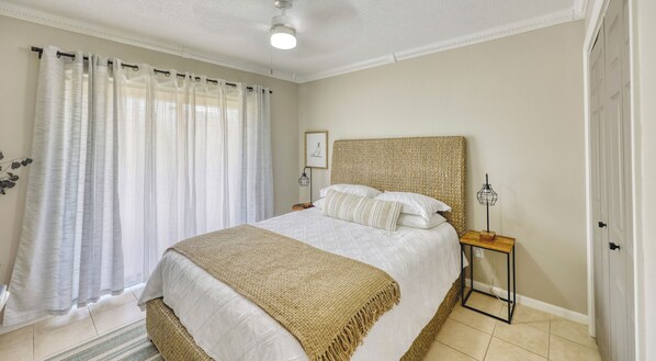 A bedroom with a bed, a bedside table, a lamp, and a window with curtains.