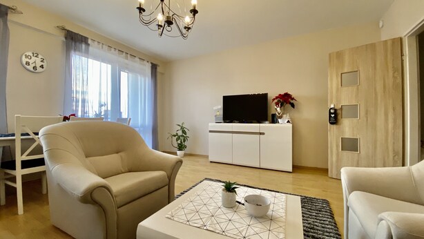 A living room with a sofa, a coffee table, a TV, and a door with a lock. - Cosy Apartament in Rzeszów City Centre (Rzeszów)