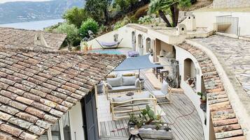 Une terrasse sur le toit avec une piscine, des espaces de détente et une vue sur la mer.
