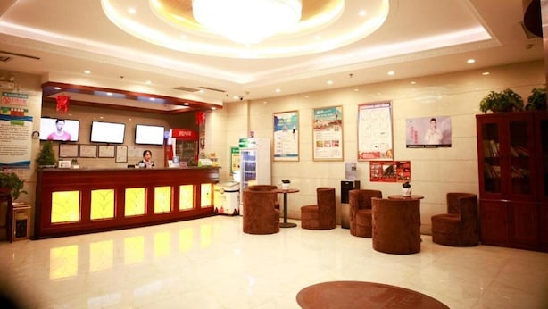 A hotel lobby with a reception desk, seating area, and a chandelier.