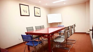 A conference room with a long table, six chairs, a whiteboard, and two framed pictures on the wall.