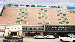 A hotel building with multiple floors, a green sign above the entrance, and a K-Boxing gym on the ground floor.