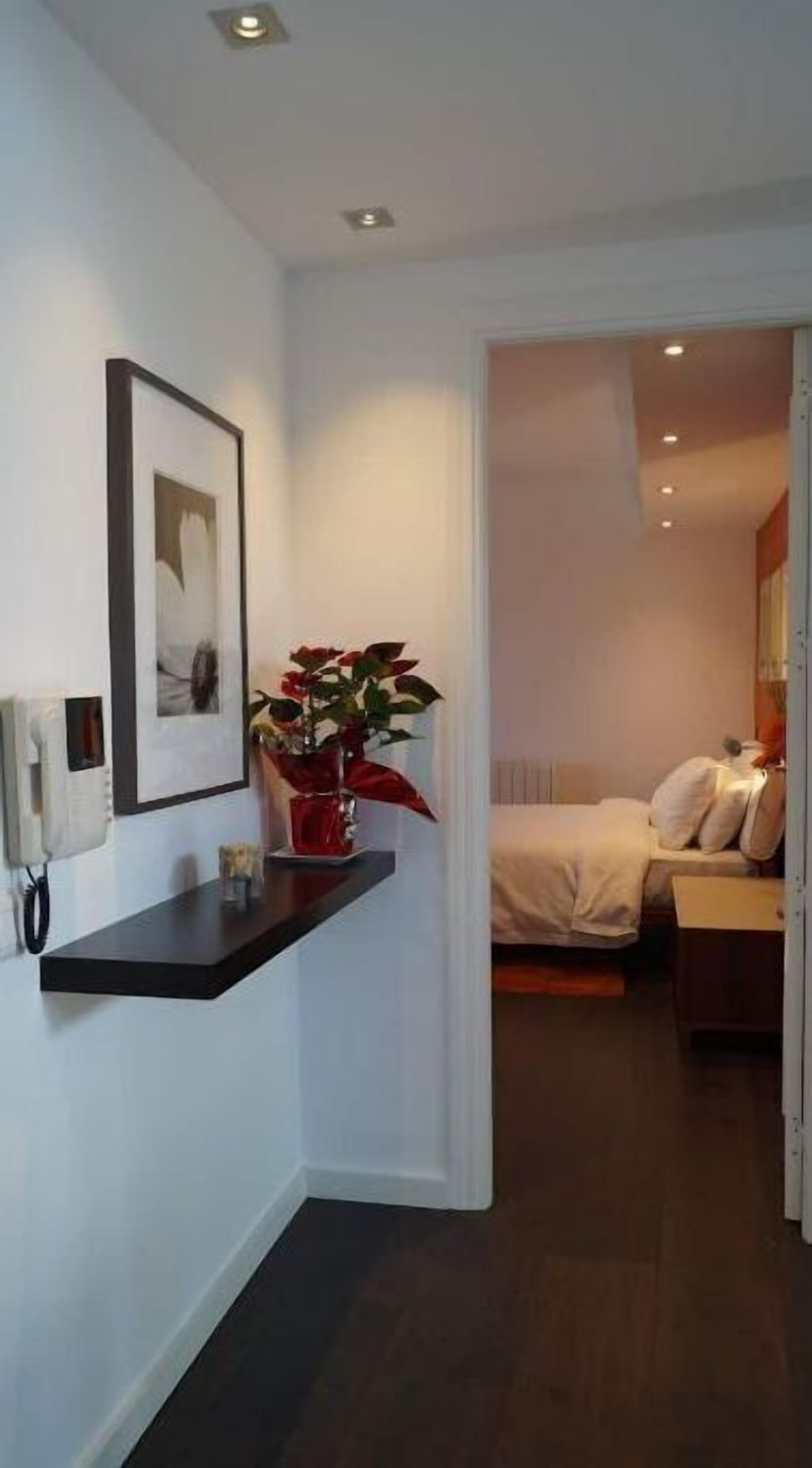 Une chambre d’hôtel comprenant un lit, une table de chevet, une commode, un miroir et un téléphone fixé au mur.