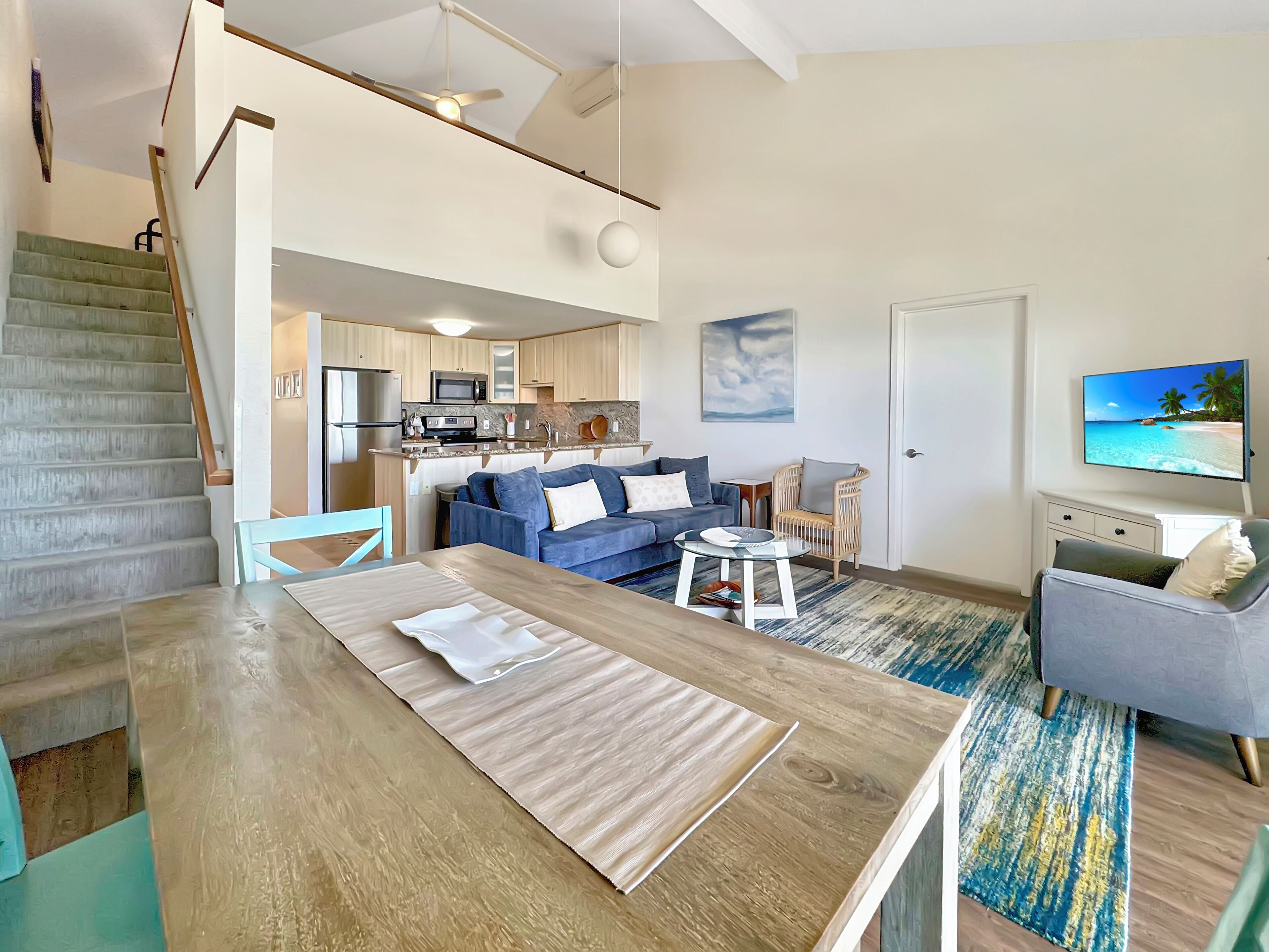 A modern apartment with a kitchen, dining area, living room, and a staircase.