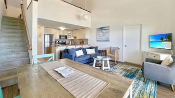 A modern apartment with a kitchen, dining area, living room, and a staircase.