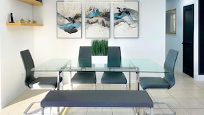 Een moderne eetruimte met een glazen tafel, zwarte stoelen, een bank en een kroonluchter.