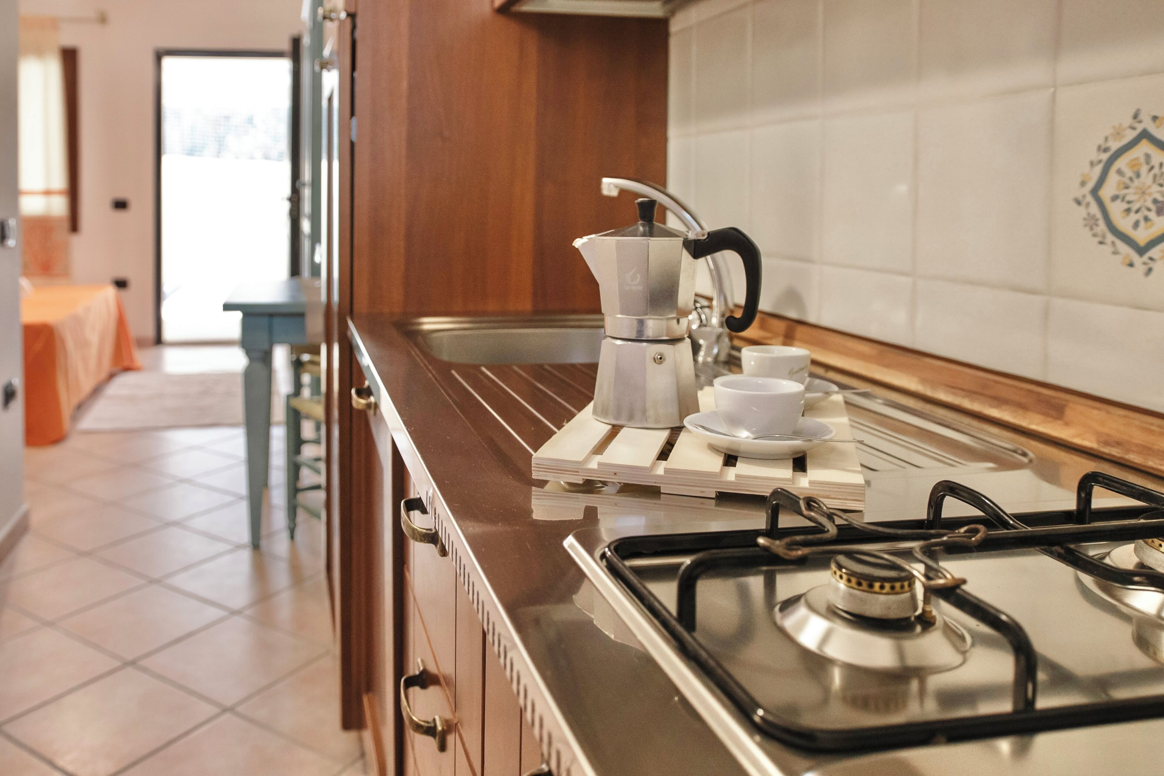 Una cucina con un piano cottura a gas, una macchina per il caffè e un lavandino.