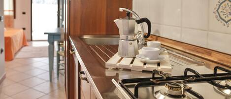 A kitchen with a gas stove, a coffee maker, and a sink.