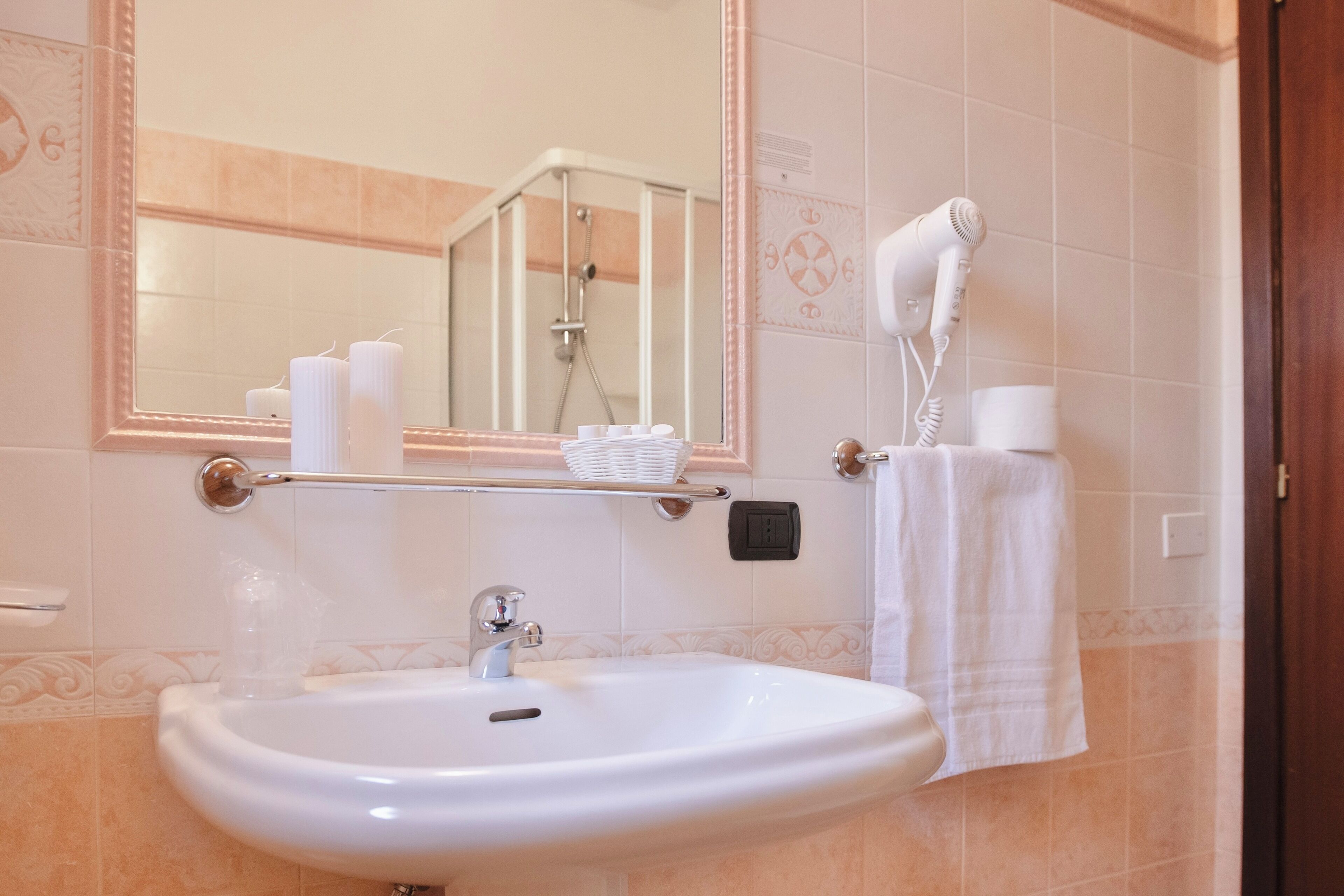 Ein Badezimmer mit Waschbecken, Spiegel, Fön und Handtuchhalter.