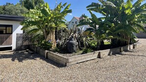 A garden with banana trees and a concrete planter. - Maygrove Retreat - Sleeps 2 - Jacuzzi & Boat Hire (Staines)