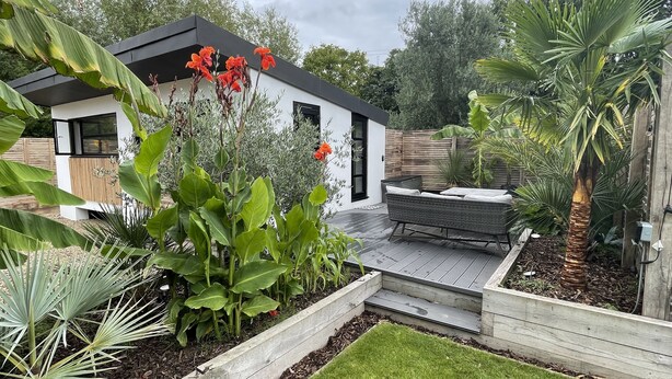 A modern house with a patio, a garden with various plants, and a wooden deck. - Maygrove Retreat - Sleeps 2 - Jacuzzi & Boat Hire (Staines)