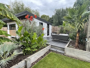 Une maison moderne dotée d’un patio, d’un jardin avec différentes espèces de plantes et d’une terrasse en bois.