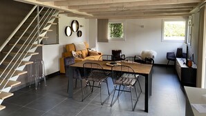 A modern interior with a dining area, a sofa, a staircase, and a computer desk. - CHARMING, COSY DUPLEX CHALET BETWEEN LAKE AND MOUNTAINS (Dingy-Saint-Clair)
