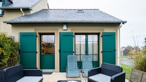 En patio med to fletsofaer, et bord med en bakke mad og to liggestole.