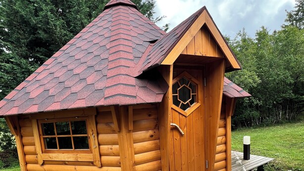 A small wooden cabin with a red-tiled roof, a wooden door with a window, and a small porch. - Enchanted cabin with shared pool/SPA and optional Kota grill (Loray)