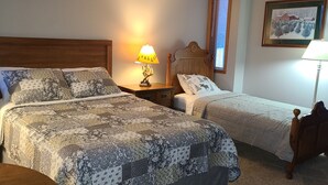 Un dormitorio con dos camas, una mesita de noche, una lámpara y un cuadro en la pared.