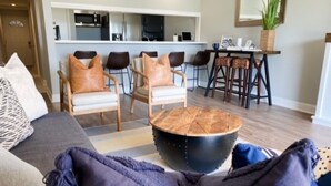 A modern living room with a sofa, a coffee table, and a dining area with chairs and a table. - Waterfront Walden Lodge! Discounted Monthly Stays! (Montgomery)