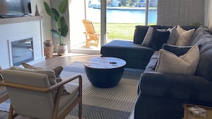 A modern living room with a sofa, armchairs, a coffee table, and a TV. - Waterfront Walden Lodge! Discounted Monthly Stays! (Montgomery)
