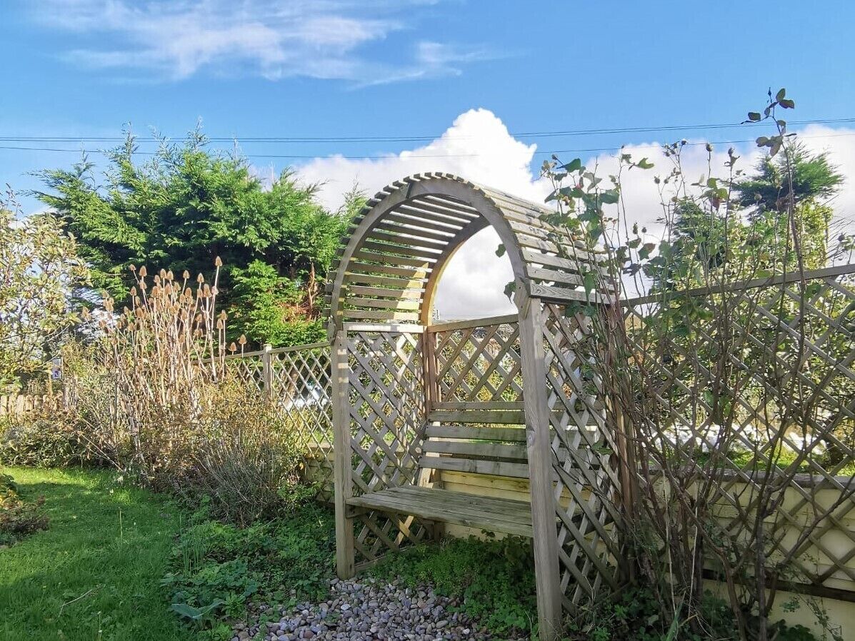 A wooden pergola structure in a garden setting.