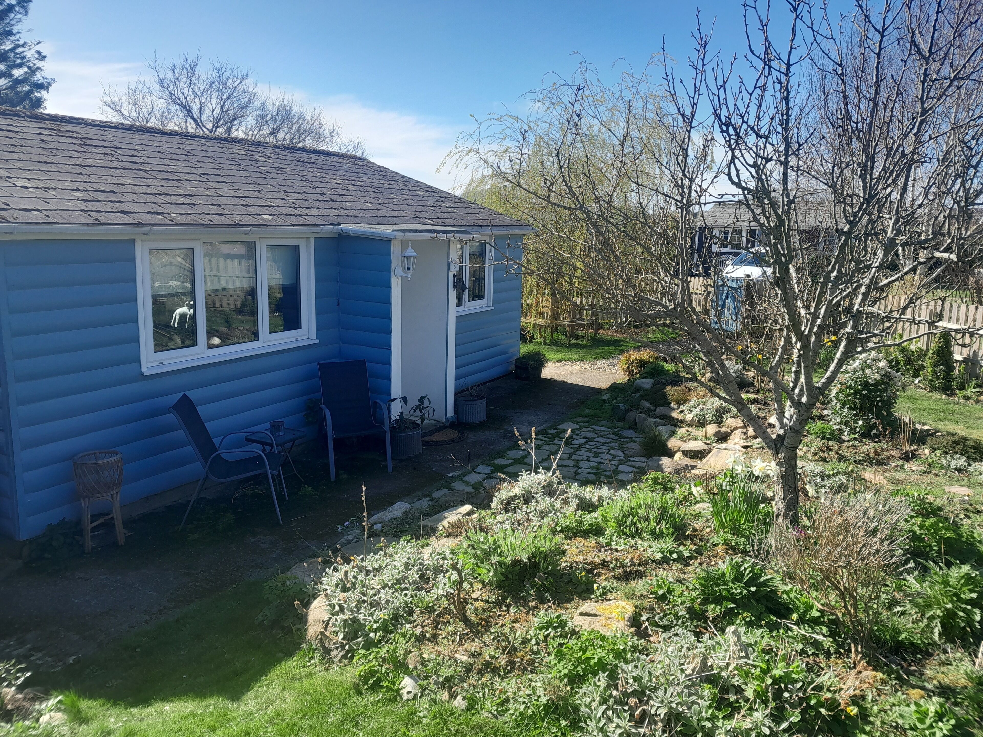 Une maison bleue avec un chemin de pierre menant à un espace patio.