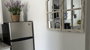 A kitchen with a stainless steel refrigerator, a white cabinet, and a decorative mirror with a distressed frame. - little paradise (Tampa)