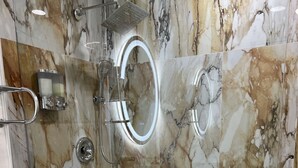 Un baño moderno con ducha de vidrio, paredes de mármol y un inodoro blanco.