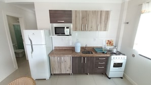 Eine kleine Küche mit Kühlschrank, Mikrowelle, Spüle und Herd.
