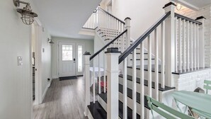 Ein Flur mit Treppe, weißen Wänden und einer Tür am Ende.