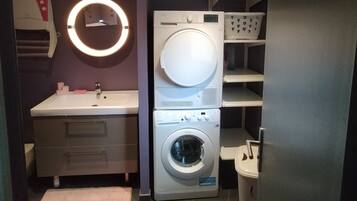 Une petite buanderie équipée d’un lave-linge, d’un sèche-linge et d’un miroir avec éclairage.