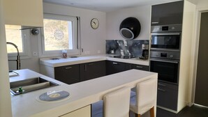 Una cocina moderna con horno empotrado, cafetera y un reloj en la pared.