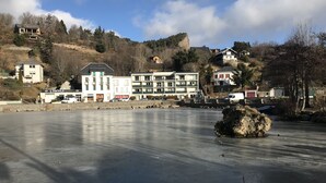 Una propiedad frente al agua con un lago helado, edificios con balcones y montañas al fondo.