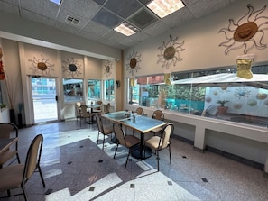 A restaurant interior with tables and chairs, sun-shaped wall decorations, and a view through the window. - Real Inn De Tijuana Boulevard Agua Caliente (Tijuana)