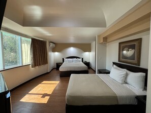 A hotel room with a large bed, a bedside table, a nightstand, a window with curtains, and a framed picture on the wall. - Real Inn De Tijuana Boulevard Agua Caliente (Tijuana)
