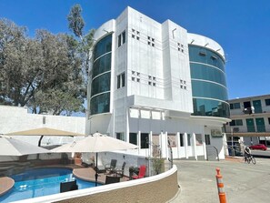 A modern building with a pool area, outdoor seating, and a clear sky. - Real Inn De Tijuana Boulevard Agua Caliente (Tijuana)