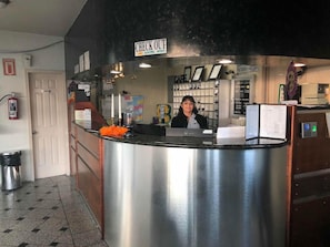 A reception desk with a 'CHECK OUT' sign, a fire extinguisher, and a trash bin. - Real Inn De Tijuana Boulevard Agua Caliente (Tijuana)