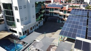 A building with a swimming pool, solar panels, and a multi-story structure with balconies.