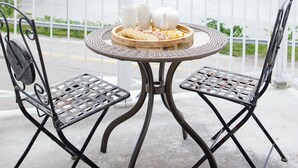 Een balkon met een tafel en stoelen, met uitzicht op een rivier en een brug.