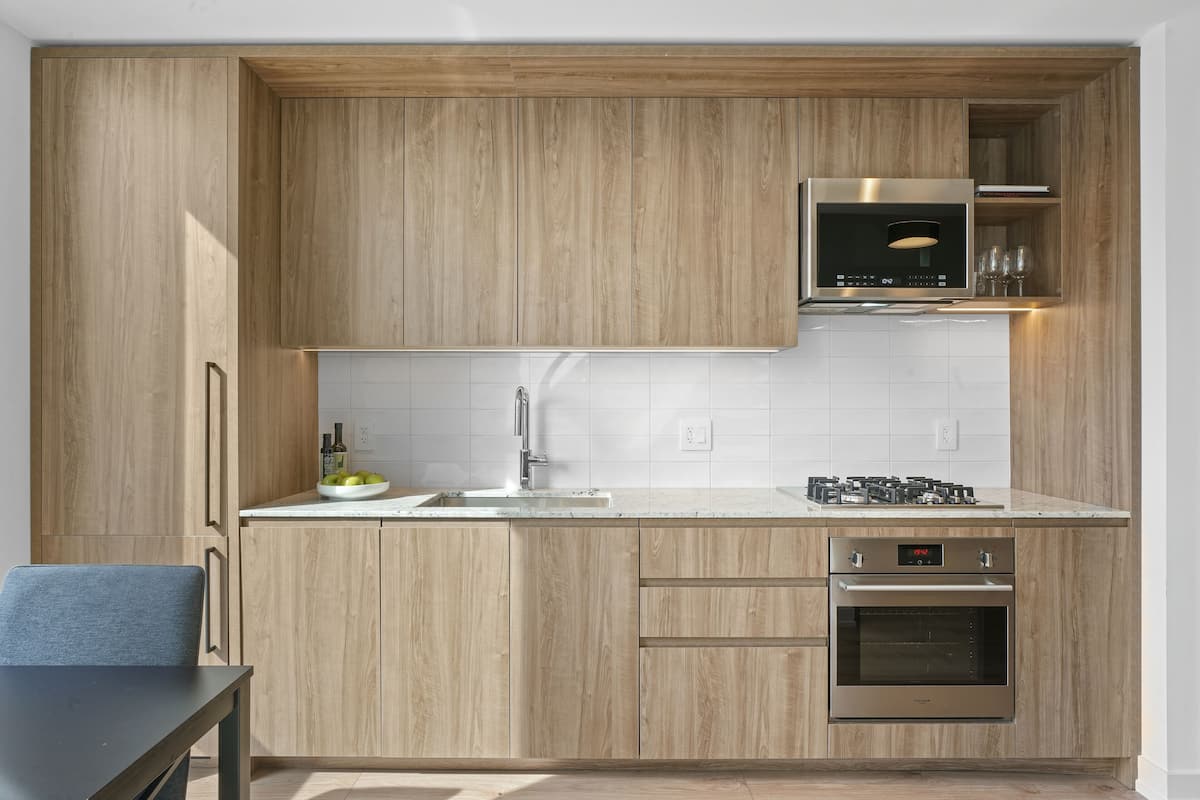 Une cuisine moderne avec des meubles en bois, un four en acier inoxydable et un four à micro-ondes.