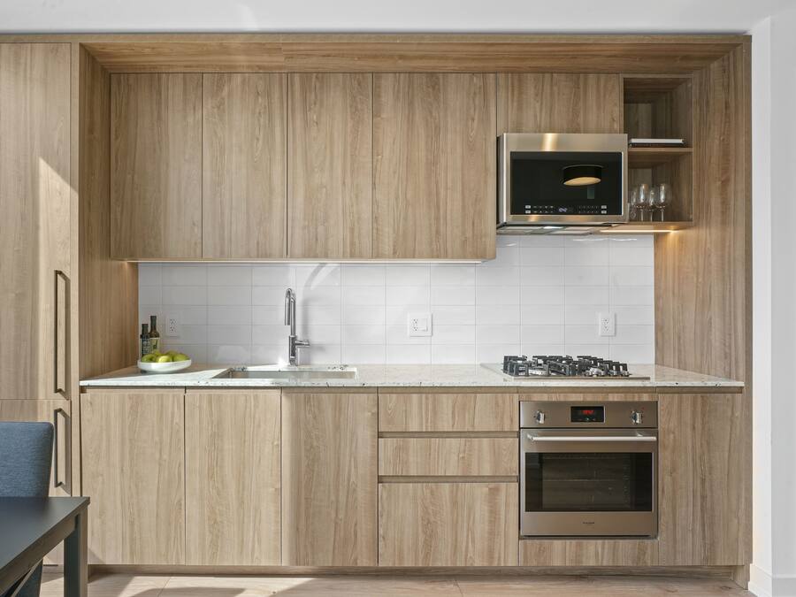 A modern kitchen with wooden cabinets, a stainless steel oven, and a microwave.