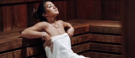 A person lying on a wooden bench in a room with wooden walls and benches.