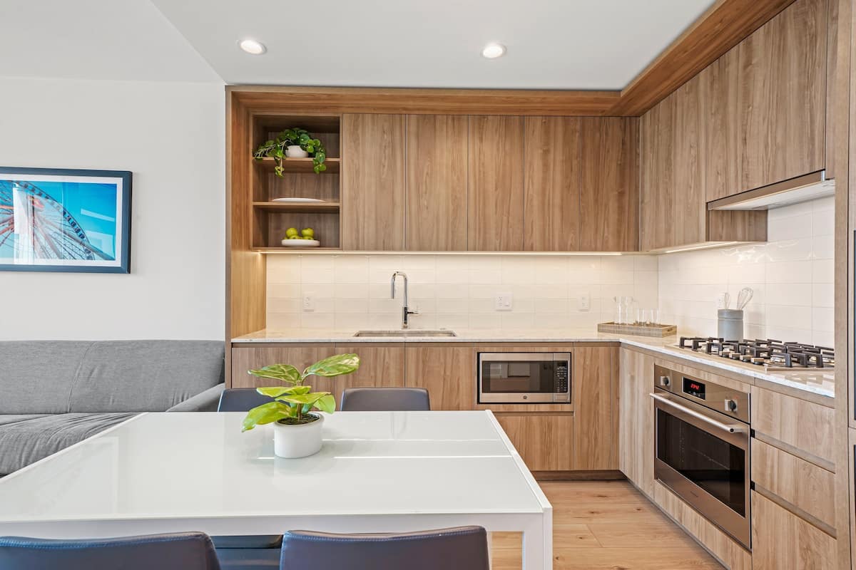 Une cuisine moderne avec des meubles en bois, un plan de travail blanc et un four encastré.