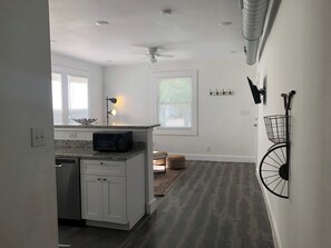 Modern kitchen with white cabinetry, granite countertop, and a black microwave.