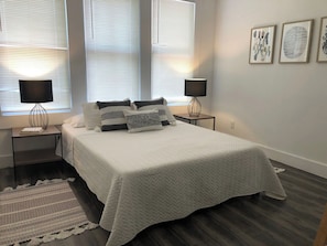 Relax in this serene bedroom with a large bed, two bedside tables, and a unique lamp design.