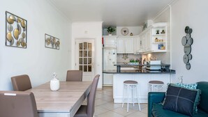 A modern kitchen with white cabinets, a central island, and a dining area with a wooden table and chairs. - Apartment for 4 with privileged access to the beach (Albufeira)